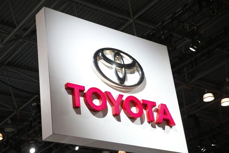 Toyota logo with red TOYOTA text on a white hanging sign at an indoor event or showroom.